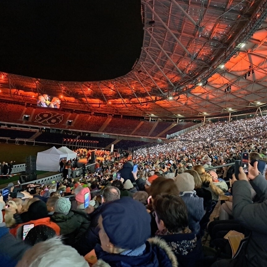 Viele Menschen sitzen auf der Tribüne der Heinz-von-Heiden Arena mit Handykameras in der Hand und singen Weihnachtslieder